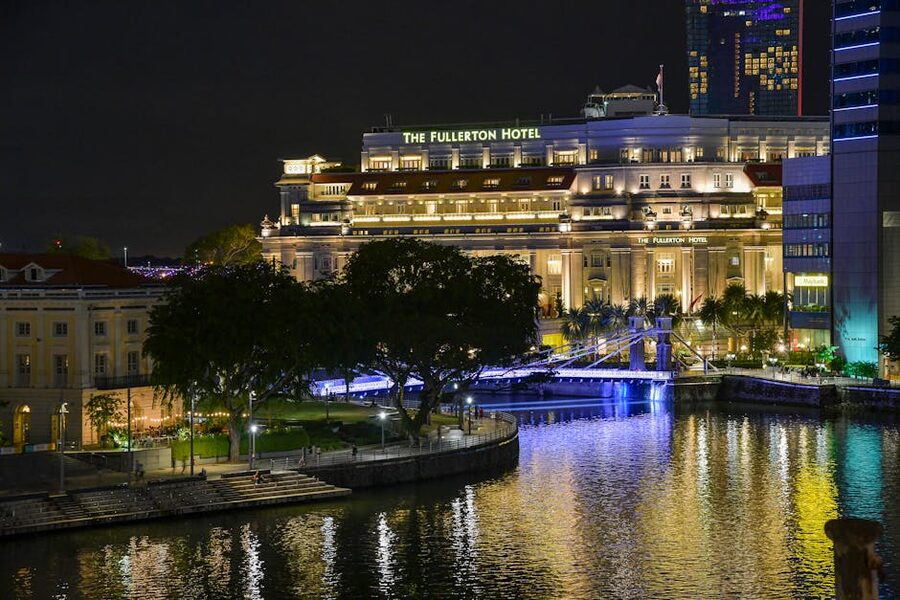 The white colonial facade and arched verandahs of Raffles Hotel Singapore at sunset