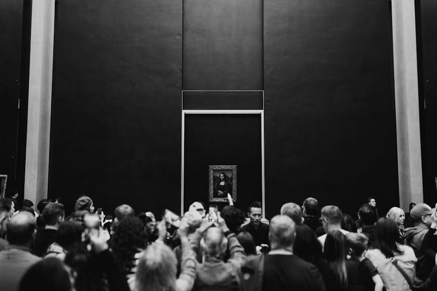 Crowds gathered in front of the Mona Lisa behind glass in the Salle des Etats at the Louvre