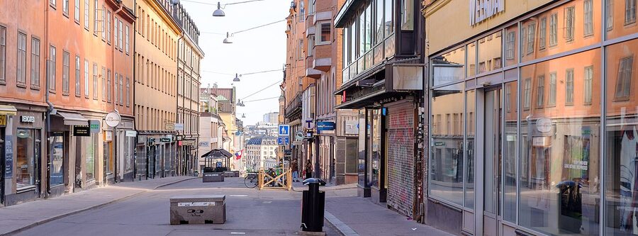 People walking along Götgatan in Söder Stockholm on a summer evening with shopfronts lit