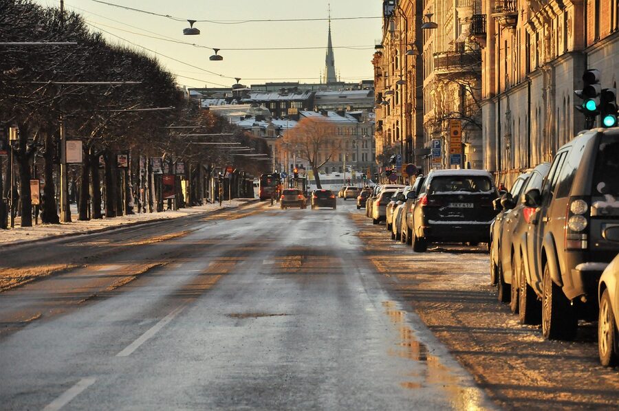 A wintry December street in Stockholm with snow on parked cars and low Scandinavian sun