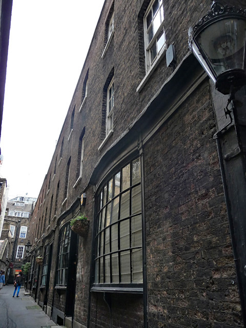 The narrow black-painted lane of Goodwin's Court in London with bow windows and gas-style lamps