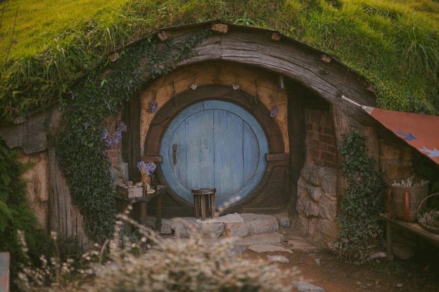 Wooden door of a hobbit hole at Hobbiton framed by climbing ivy