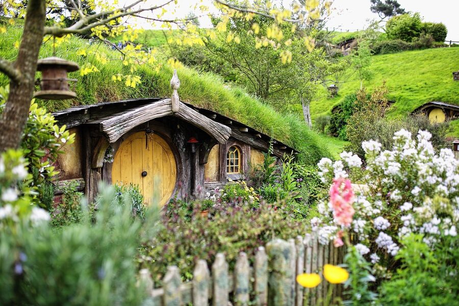 Wide view of the Hobbiton movie set valley with hobbit holes set into rolling hills