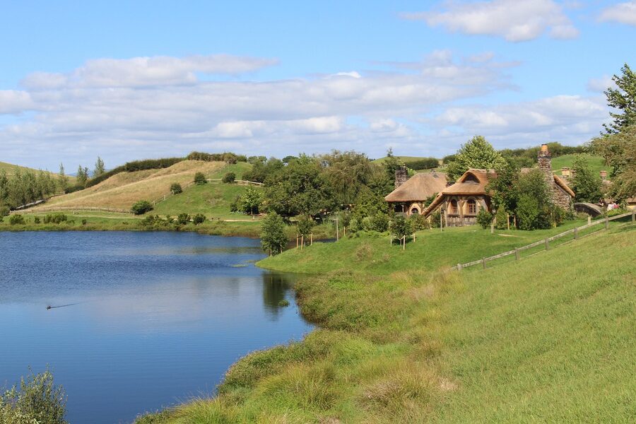 Hobbiton thatched roofs and gardens beneath blue summer sky