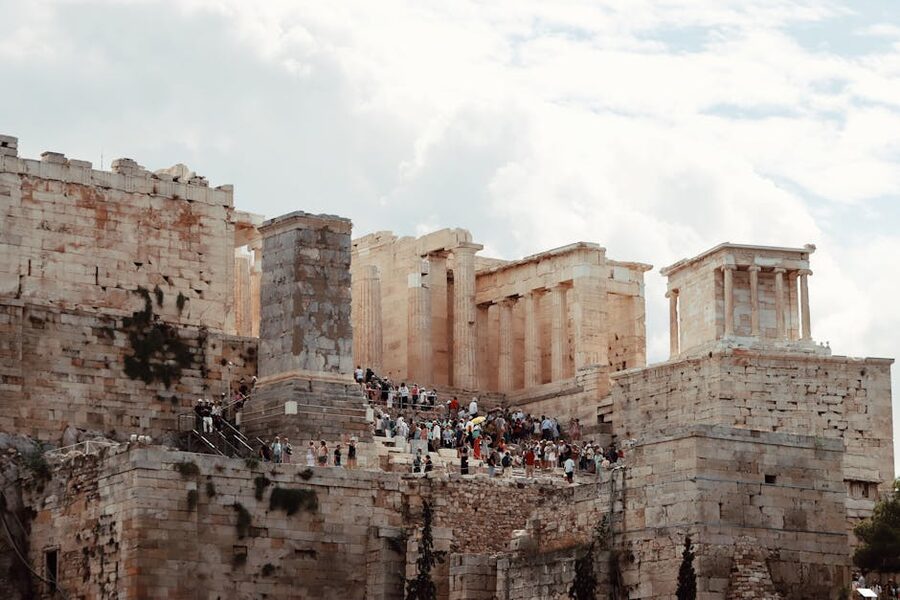 The Parthenon temple on the Acropolis of Athens with tourists at its base under a clear blue sky
