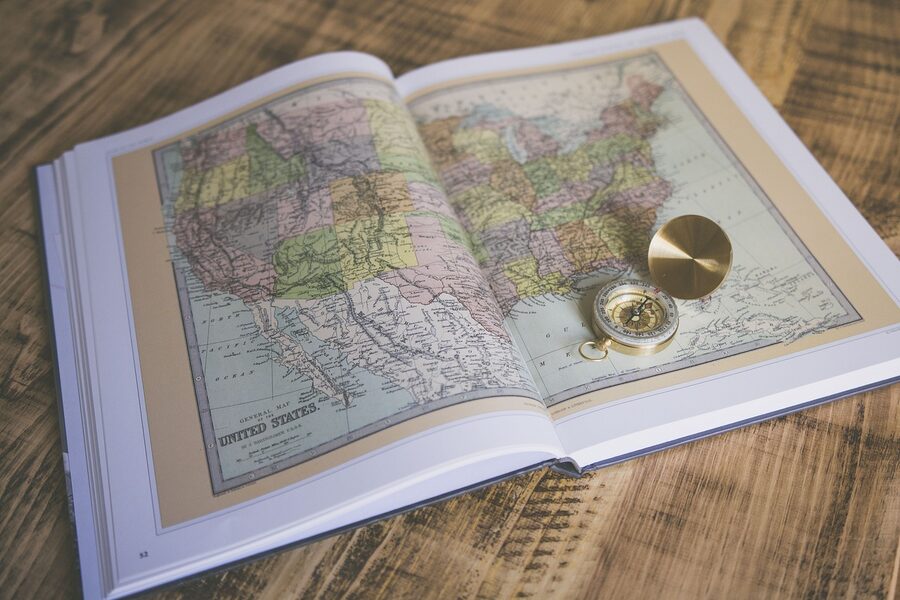 An open atlas with a compass and travel reading material, ready to plan a trip