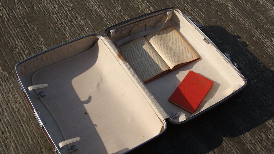 An open vintage suitcase filled with paperbacks sitting on a sunlit pavement