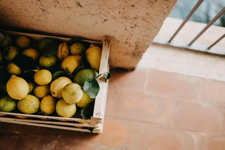 A wooden crate of fresh lemons with leaves still attached, the variety locally cultivated on Procida