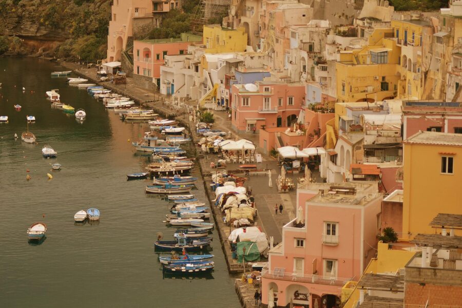 The pastel-coloured fishing houses of Marina Corricella on Procida with small boats moored in the harbour