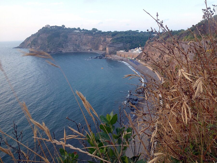 Cala Pozzo Vecchio beach on the west side of Procida with black volcanic sand and steep cliffs behind