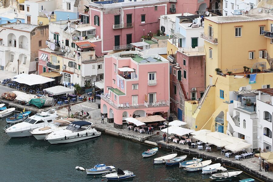 A narrow cobbled lane in the Corricella quarter of Procida lined with painted houses and laundry hanging across the alley